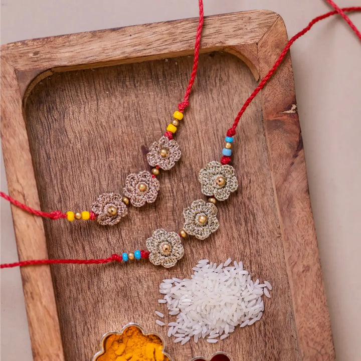 Handmade Crochet Golden Floral Rakhi With Roli Chawal Set Of 2 - Close-up on Rakhi Bracelets