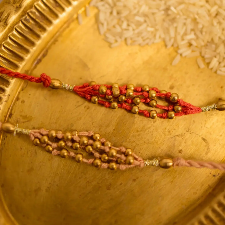 Handmade Crochet Noori Moti Rakhi With Roli Chawal Set Of 2 - Close-up of red and gold beads