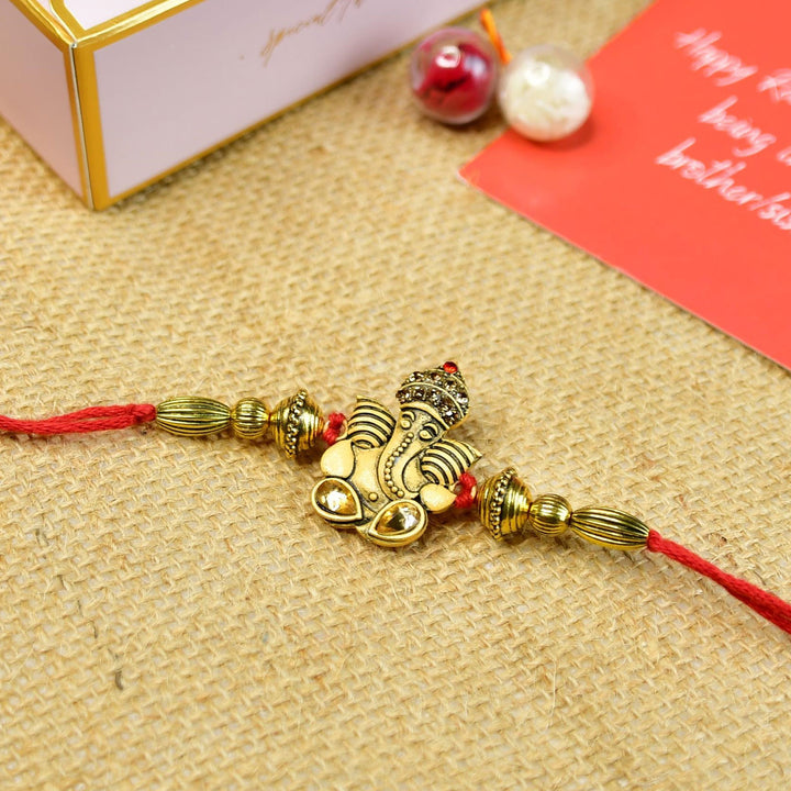Beaded Golden Ganesha Rakhi With Chocolates And Roli Chawal For Brother Customizable Options Includes Up To 7 Goodies - Angled Close-up View