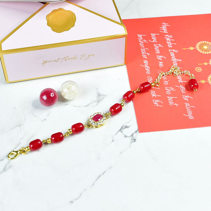Beaded Red Pearl And Stone Bracelet Rakhi Hamper With Chocolates And Roli Chawal For Brother Customizable Options Includes Up To 7 Goodies - Flat lay of Rakhi with packaging
