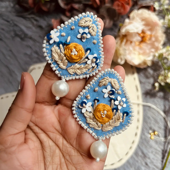 Hand Embroidered Blue Floral Bhaiya Bhabhi Rakhi With Roli Chawal Set Of 2 - Pair of pieces held in hand