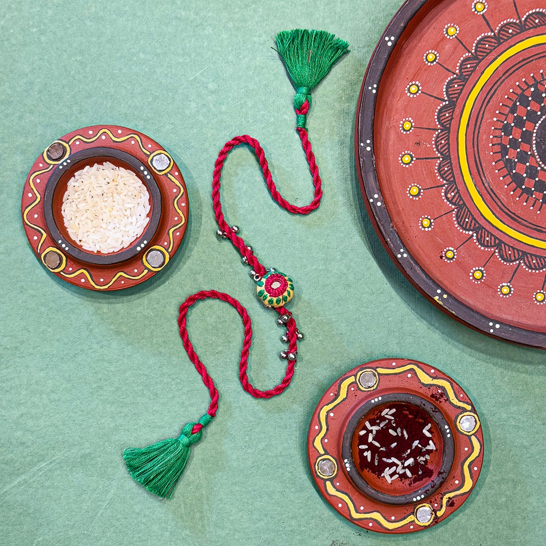 Handmade Reusable Red Potli And Jhumki Rakhi For Brother - Styled Display with Decorative Plates