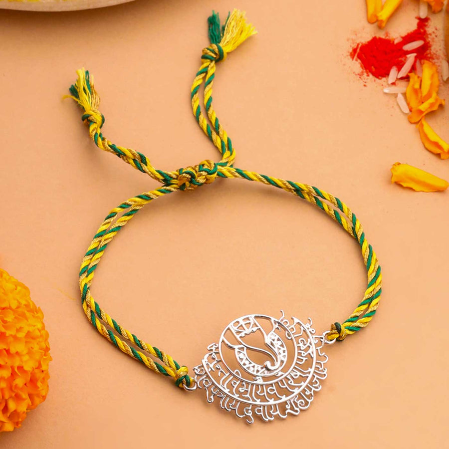 Handmade Ganesha Theme Religious Silver Rakhi For Brother - Front View with Decorative Background