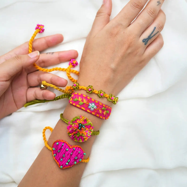 Handmade Embroidered And Beaded Pom Pom Atrangi Rakhi With Roli Chawal Set Of 4 - Bracelets worn on wrist view