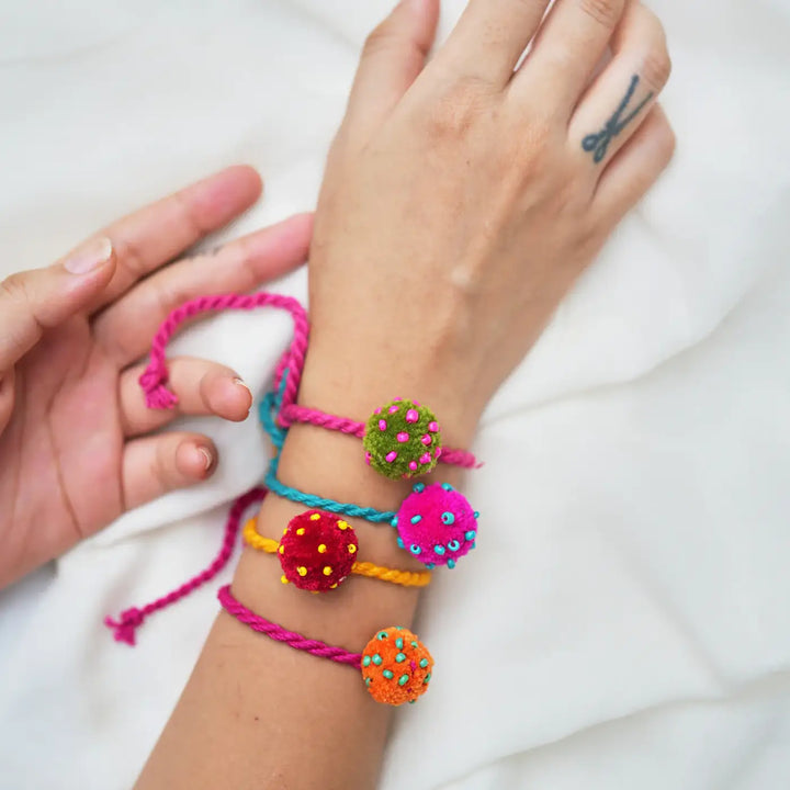 Handmade Beaded Pom Pom Mini Laddoo Rakhi With Roli Chawal Set Of 4 - Wristwear Display on Hand