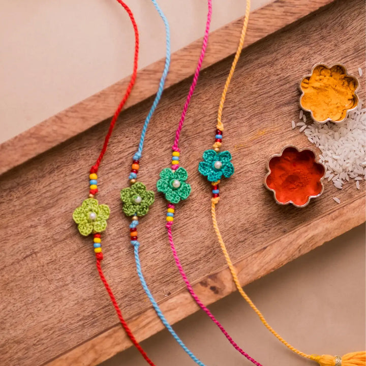 Handmade Crochet Pink Daisies Rakhi With Roli Chawal Set Of 4 - Top view of green flower bracelets and spices