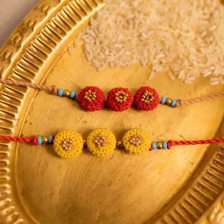 Handmade Crochet Round Ananta Rakhi With Roli Chawal Set Of 2 - Detailed macro with rice background