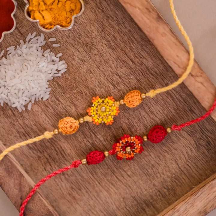 Handmade Crochet Red And Yellow Flower Rakhi With Roli Chawal Set Of 2 - Detailed View with Decorative Elements
