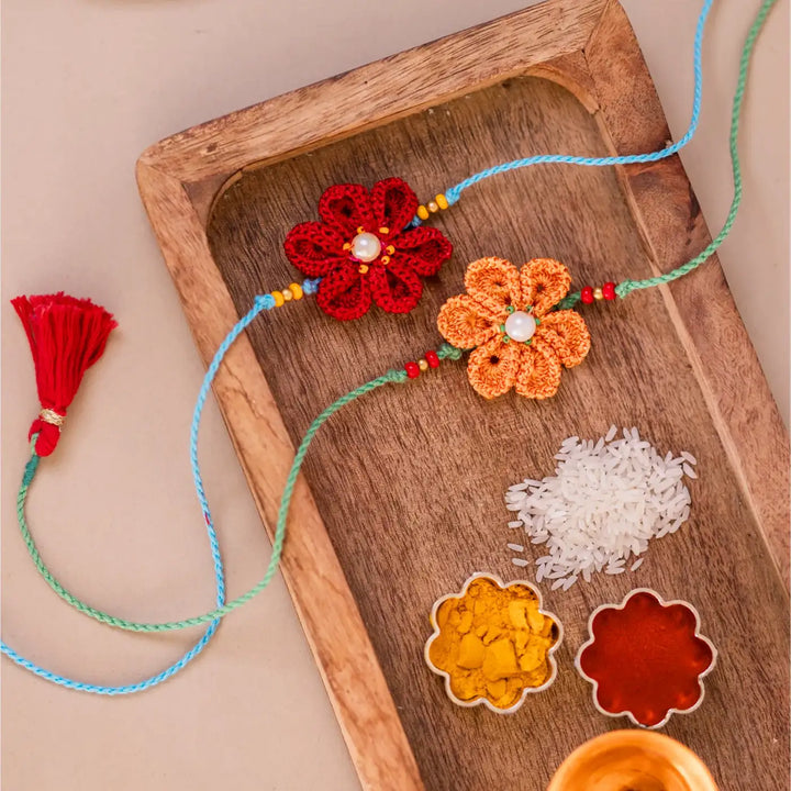 Handmade Crochet Red And Yellow Daffodil Rakhi With Roli Chawal Set Of 2 - Top View with Spices and Rice
