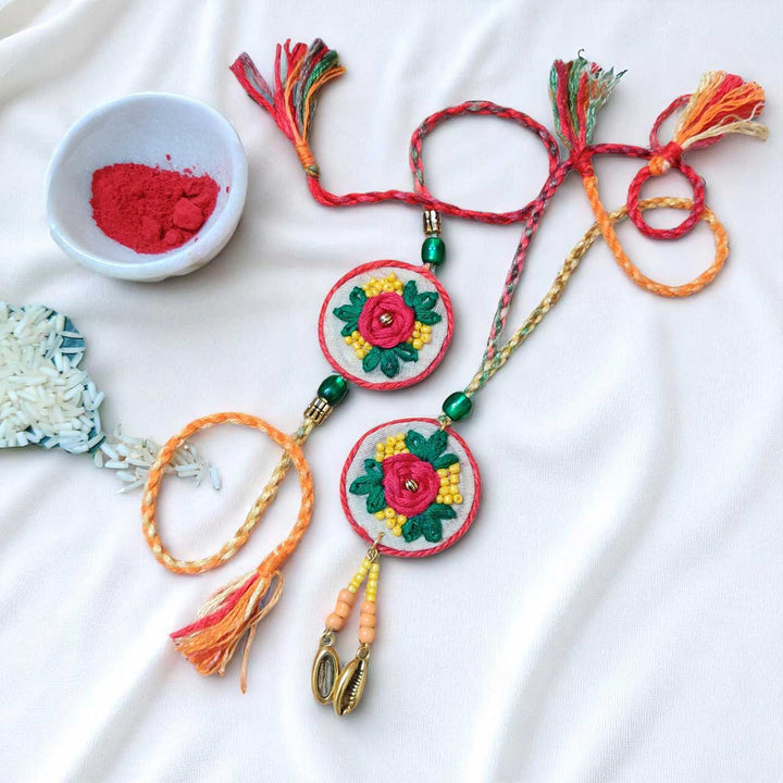 Handmade Embroidered Flower Theme Cotton Rakhi With Roli Chawal For Bhaiya And Bhabhi - Flat Lay Display with Decorative Elements