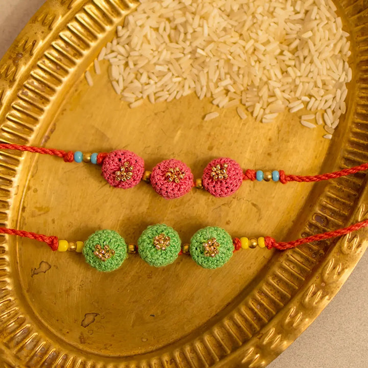 Handmade Crochet Round Ananta Rakhi With Roli Chawal Set Of 2 - Close-up of pink and green set