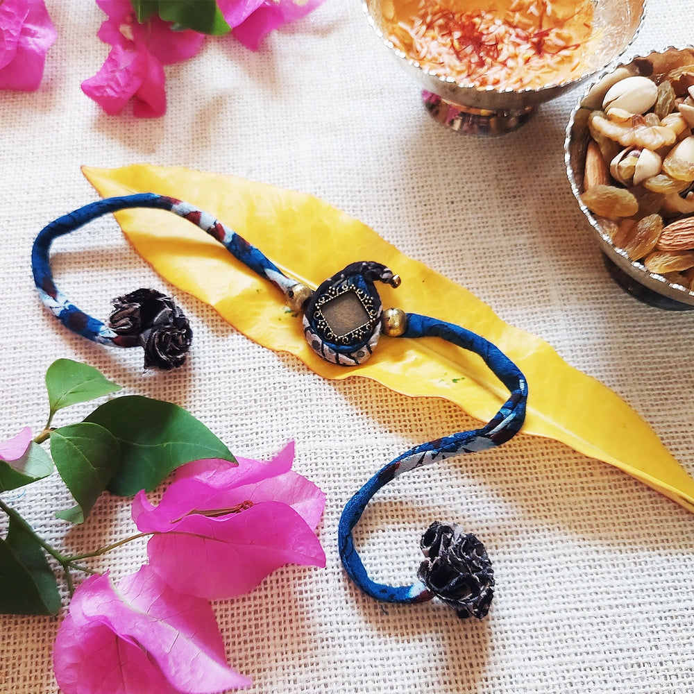 Handmade Dori Work Ambi Ajrakh Rakhi With Roli Chawal - Styled Flat Lay with Decor Items