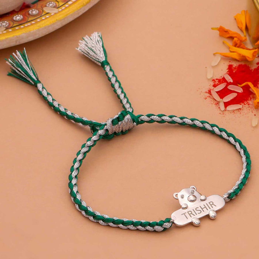 Personalized Handmade Bear Design Silver Kids Rakhi - Flat Lay with Decorative Background