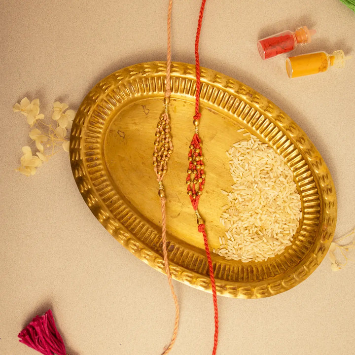 Handmade Crochet Noori Moti Rakhi With Roli Chawal Set Of 2 - Flat lay with rice heart design