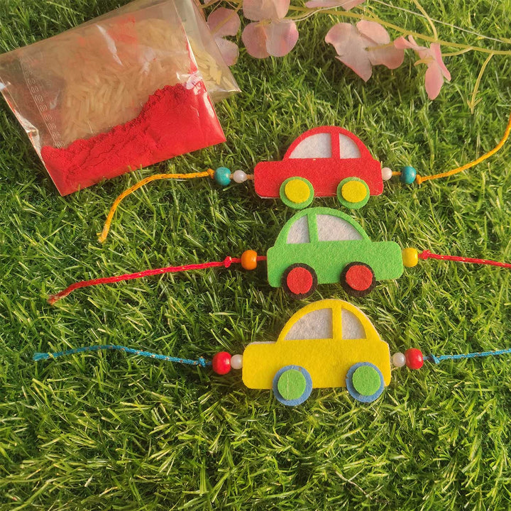 Customized Handmade Beaded Car Theme Pom Pom Felt Rakhi With Roli Chawal For Kids - Car Bracelets on Grass Background