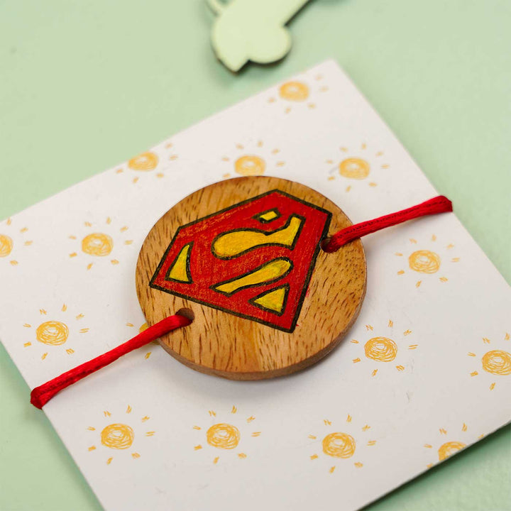 Personalized Hand Painted Super Man Wooden Rakhi With Roli Chawal - Angled View on Card