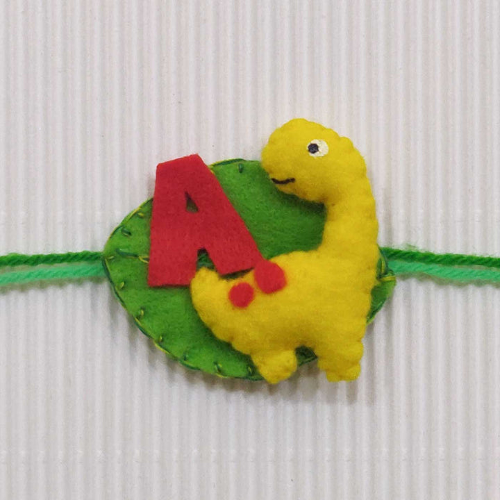 Personalized Handmade Dinosaur Theme Felt Kids Rakhi With Roli Chawal - Close-up of yellow dinosaur wristband