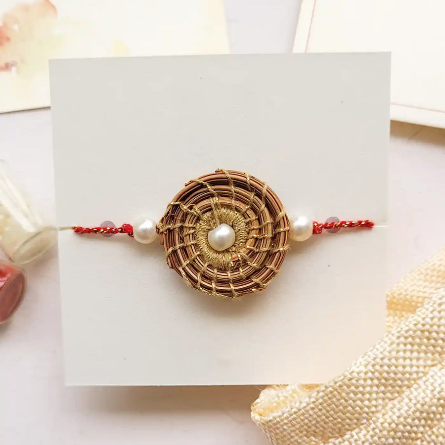 Eco Friendly Handmade Gold And Pearl Pine Needle Rakhi With Pouch And Roli Chawal - Front View