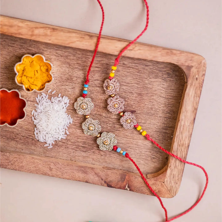 Handmade Crochet Golden Floral Rakhi With Roli Chawal Set Of 2 - Top View with Traditional Ingredients