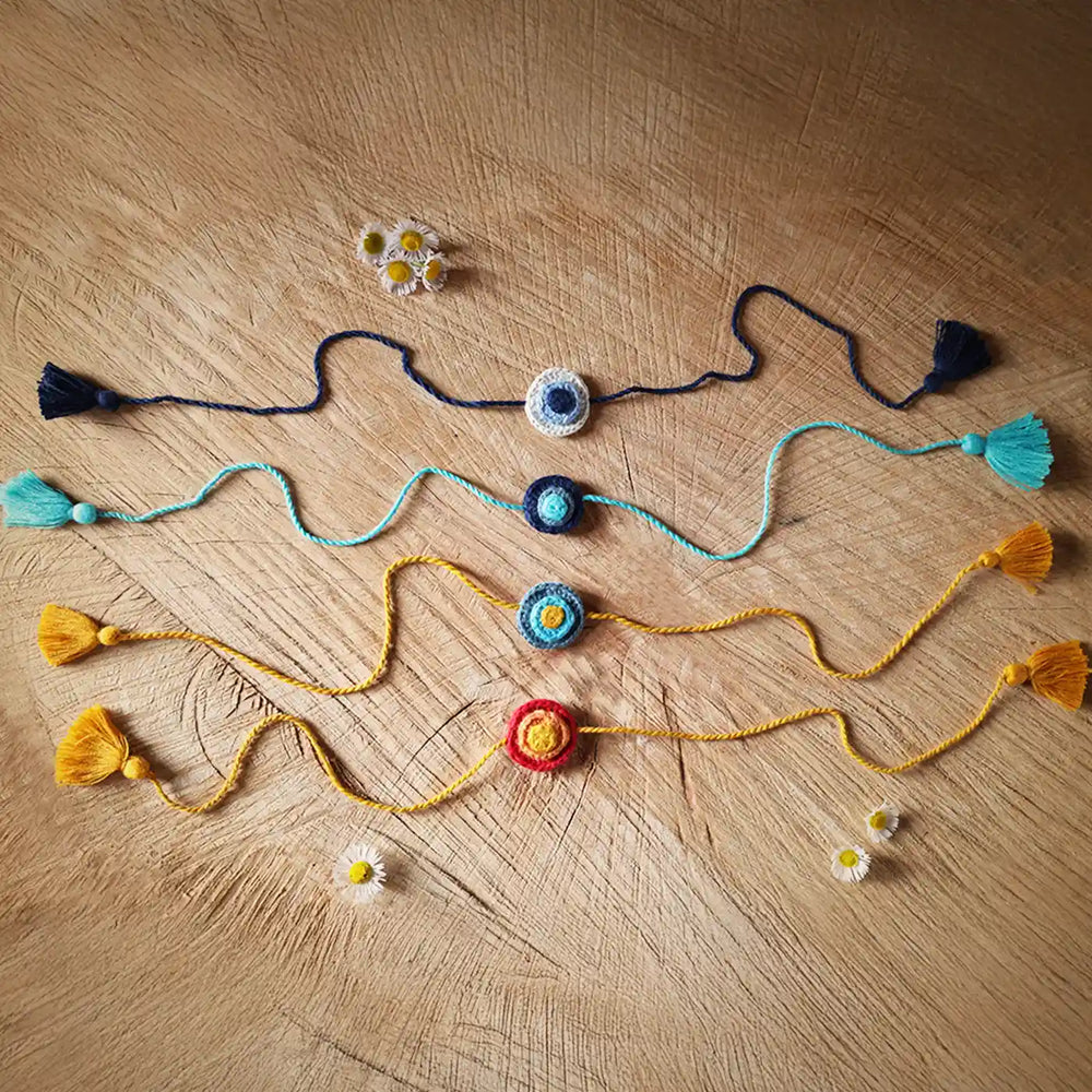 Handmade Crochet Evil Eye Rakhi With Roli Chawal Set Of 4 - Flat Lay Display with Daisies