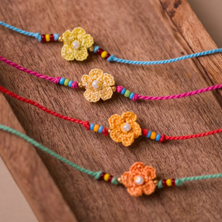 Handmade Crochet Pink Daisies Rakhi With Roli Chawal Set Of 4 - Close-up of yellow-orange thread flower bracelets