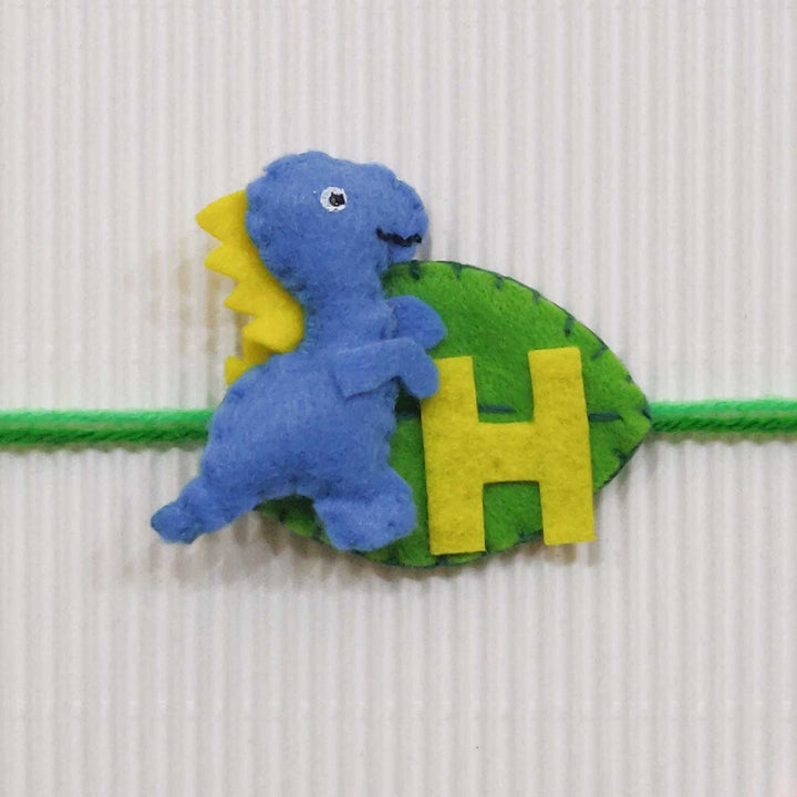 Personalized Handmade Dinosaur Theme Felt Kids Rakhi With Roli Chawal - Close-up of blue dinosaur wristband