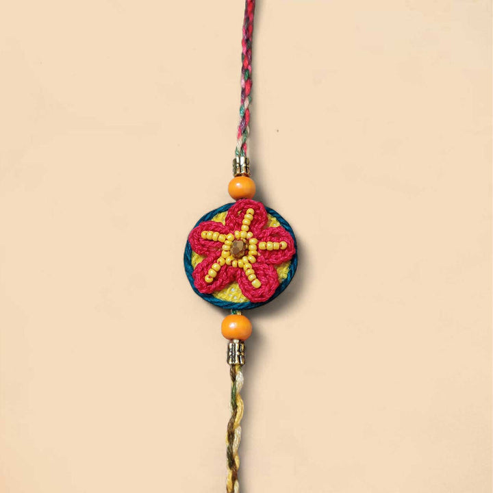 Handmade Crochet Flower Theme Cotton Rakhi With Roli Chawal - Flat lay against plain background