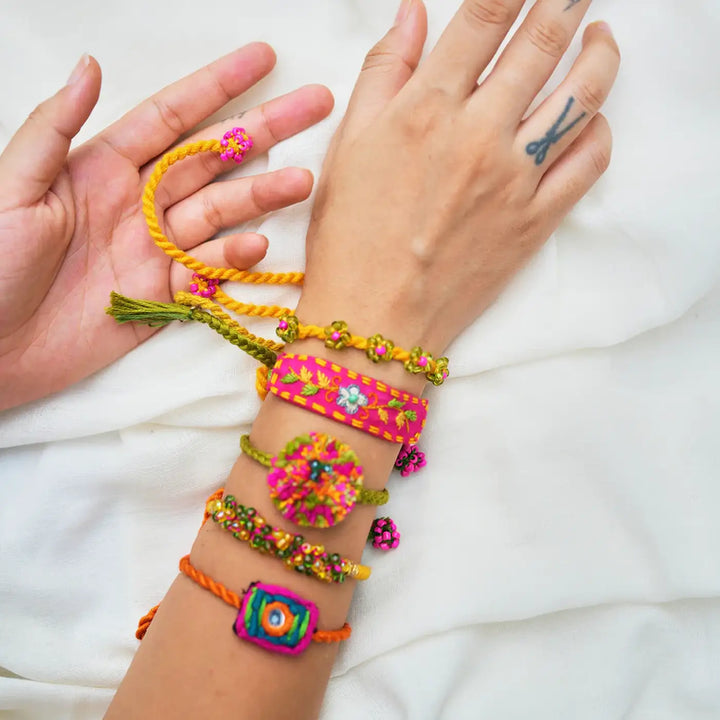 Handmade Embroidered And Beaded Chum Chum Rakhi With Roli Chawal Set Of 5 - Wrist Close-up with Green Thread Detail