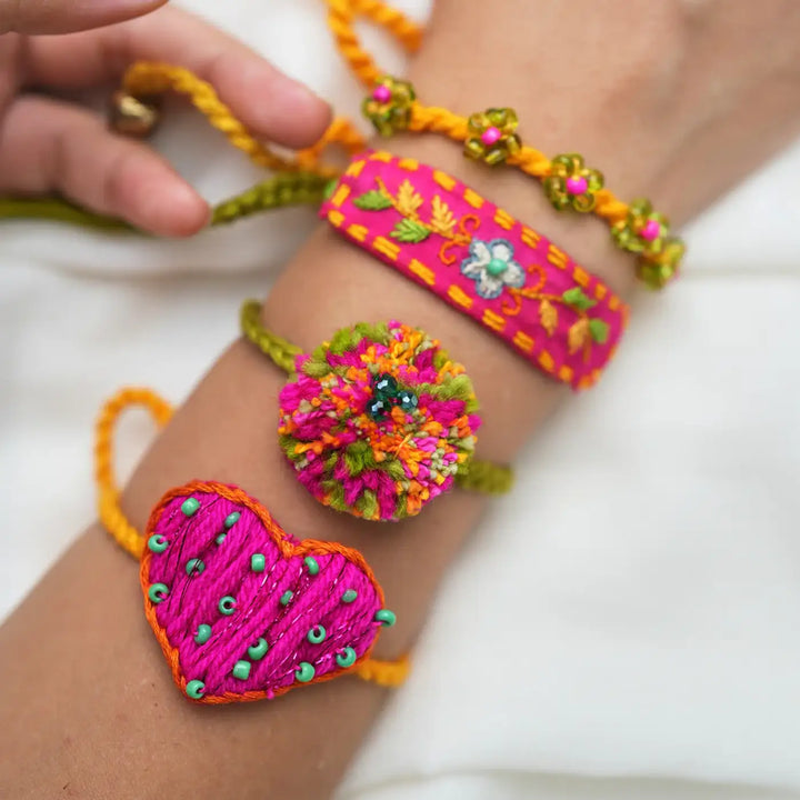 Handmade Embroidered And Beaded Pom Pom Atrangi Rakhi With Roli Chawal Set Of 4 - Close-up of bracelets on wrist