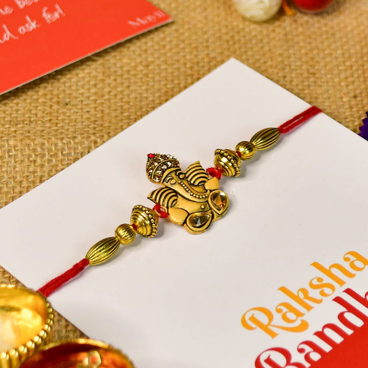 Beaded Golden Ganesha Rakhi With Chocolates And Roli Chawal For Brother Customizable Options Includes Up To 7 Goodies - Front View