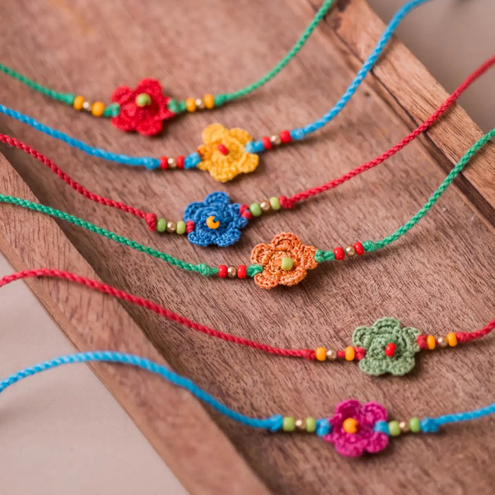 Handmade Crochet Multicolor Daisies Rakhi With Roli Chawal Set Of 6 - Close-up of flower bracelets