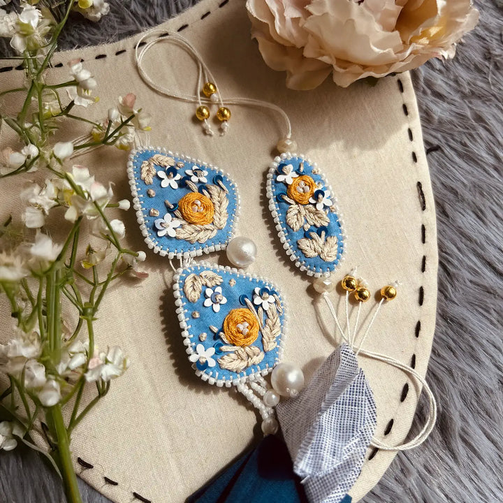 Hand Embroidered Blue Floral Bhaiya Bhabhi Rakhi With Roli Chawal Set Of 2 - Full set displayed on surface