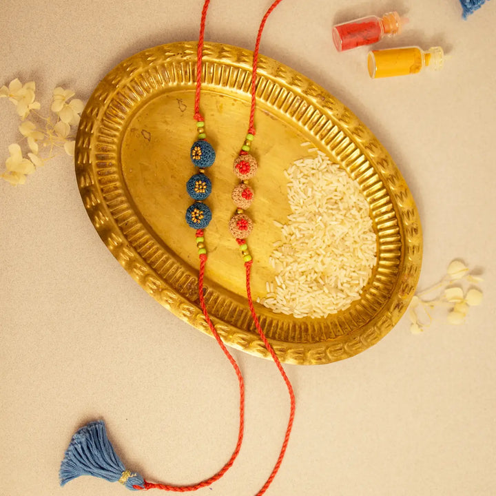 Handmade Crochet Round Ananta Rakhi With Roli Chawal Set Of 2 - Overhead view on brass tray