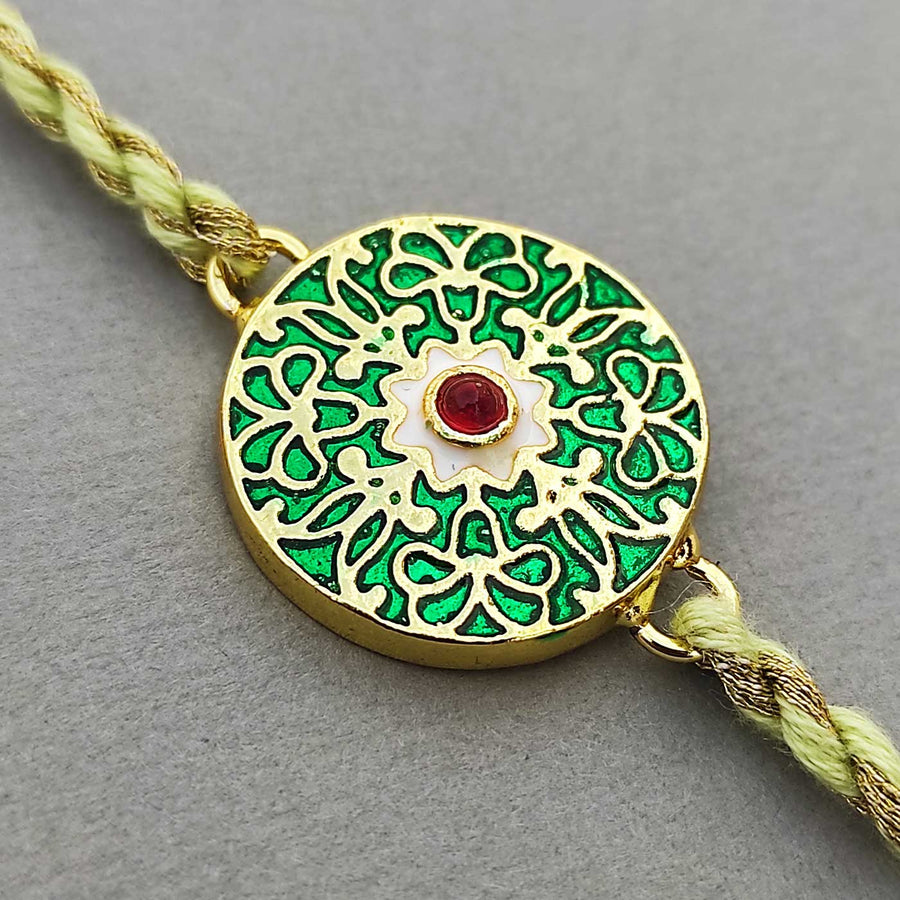 Handmade Meenakari Green Buta Brass Rakhi With Roli Chawal - Close-up of decorative centerpiece
