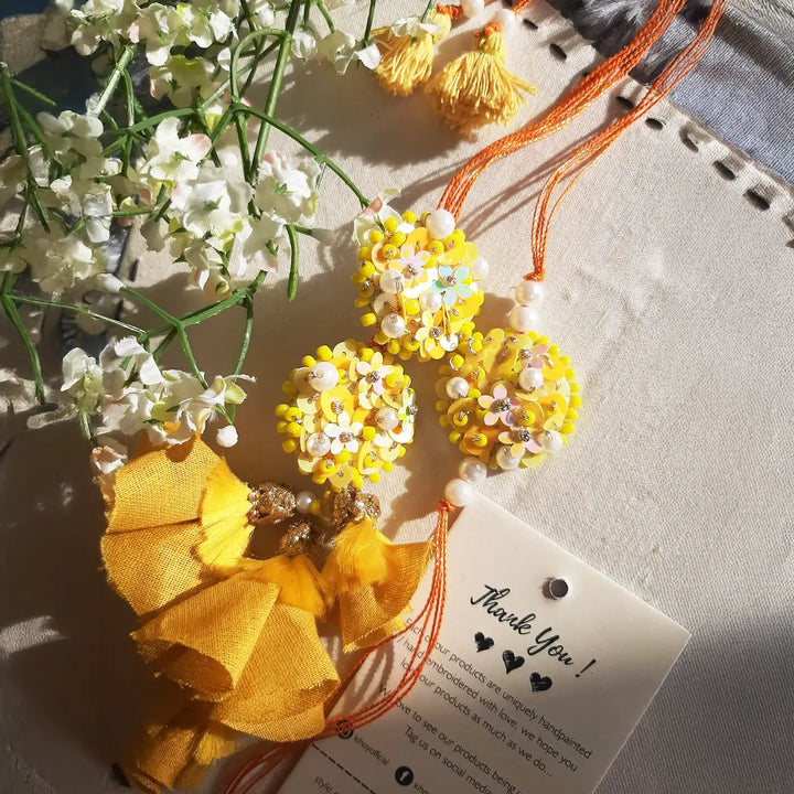 Hand Embroidered Beaded Marigold Bhaiya Bhabhi Rakhi With Roli Chawal Set Of 2 - Decorative display with flowers and tag