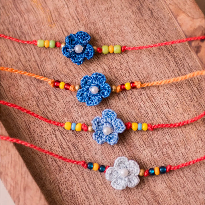 Handmade Crochet Pink Daisies Rakhi With Roli Chawal Set Of 4 - Close-up of blue flower bracelets