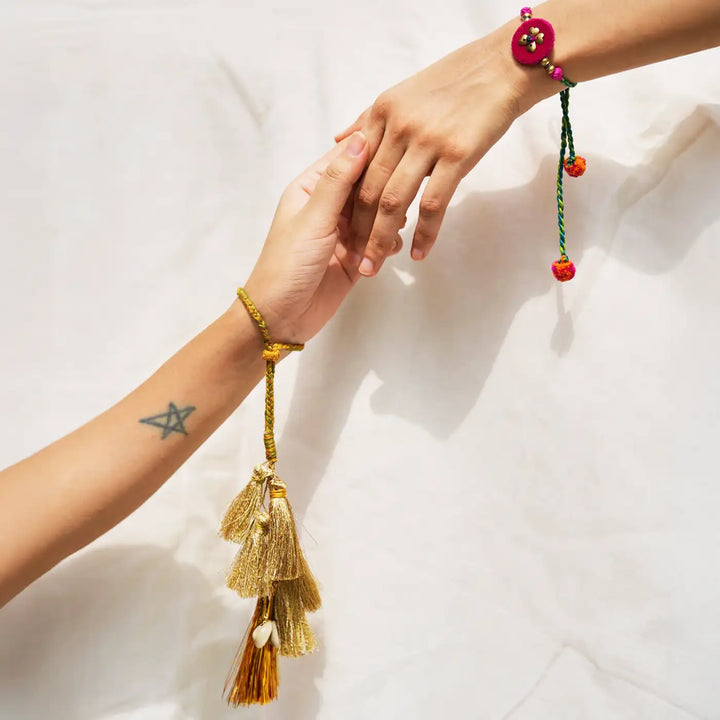 Handmade Embroidered Golden Tassels Kaju Katli Bhaiya Bhabhi Rakhi With Roli Chawal Set Of 2 - Rakhi on wrists, holding hands