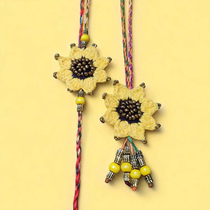 Handmade Crochet Sunflower Theme Cotton Rakhi With Roli Chawal For Bhaiya And Bhabhi - Full View on Yellow Background