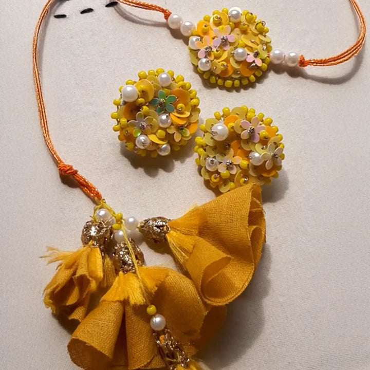 Hand Embroidered Beaded Marigold Bhaiya Bhabhi Rakhi With Roli Chawal Set Of 2 - Flat lay view on plain surface