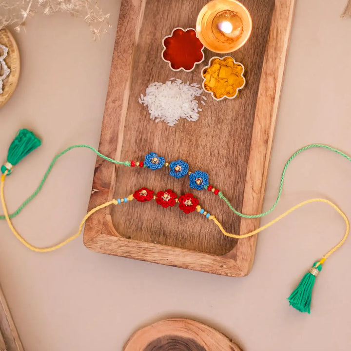 Handmade Crochet Red And Blue Floral Rakhi With Roli Chawal Set Of 2 - Styled with Traditional Elements