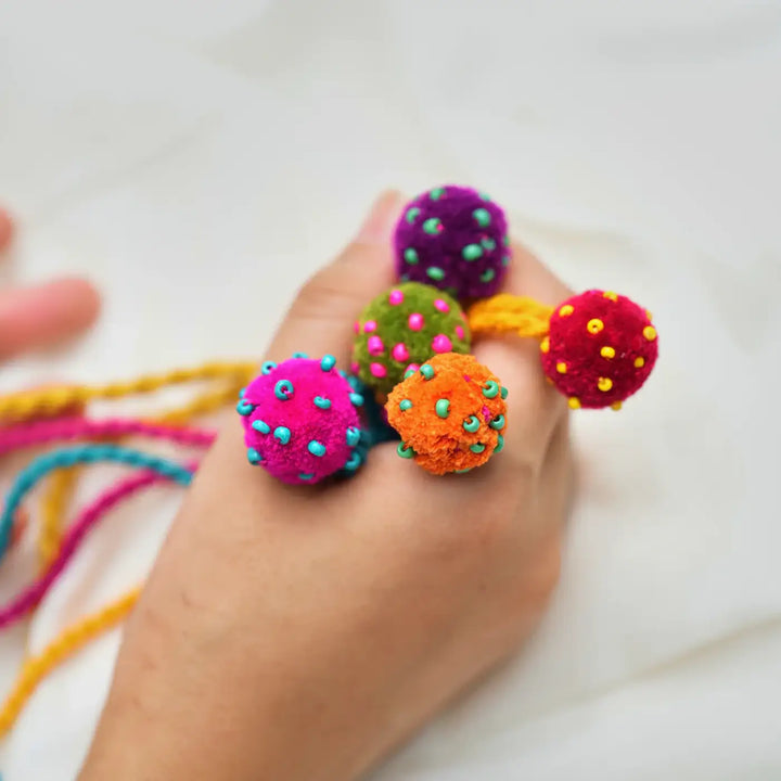 Handmade Beaded Pom Pom Mini Laddoo Rakhi With Roli Chawal Set Of 5 - Close-up of bracelets held in hand