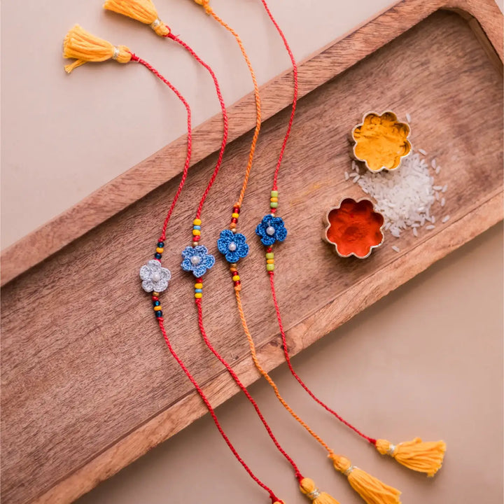 Handmade Crochet Pink Daisies Rakhi With Roli Chawal Set Of 4 - Close-up of blue flower bracelets with beads
