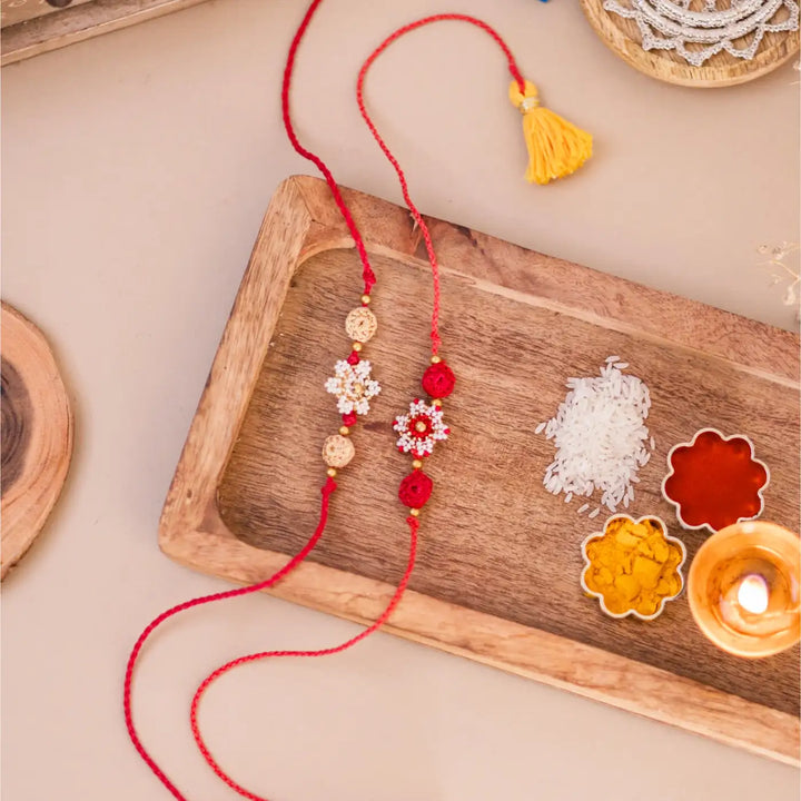 Handmade Crochet Red And White Flower Rakhi With Roli Chawal Set Of 2 - Styled flat lay with festival items