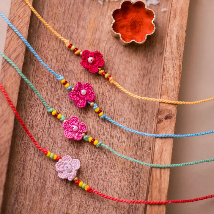 Handmade Crochet Pink Daisies Rakhi With Roli Chawal Set Of 4 - Front close-up of colorful thread bracelets