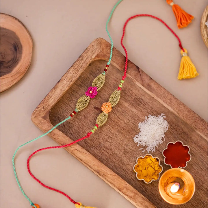 Handmade Crochet Bageeya Rakhi With Roli Chawal Set Of 2 - Styled Display with Rice and Candle