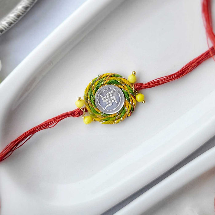 Handmade Beaded Swatik Design Silver Rakhi Hamper With Roli Chawal For Bhaiya And Bhabhi - Flat Lay Single Rakhi Thread