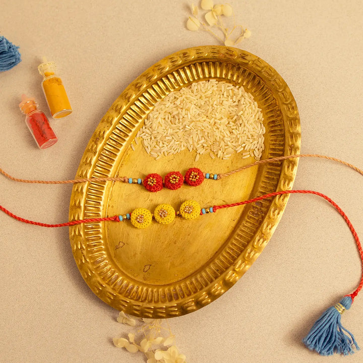 Handmade Crochet Round Ananta Rakhi With Roli Chawal Set Of 2 - Close-up of red and yellow set