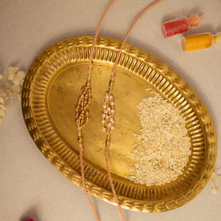 Handmade Crochet Noori Moti Rakhi With Roli Chawal Set Of 2 - Flat lay with pink bead focus