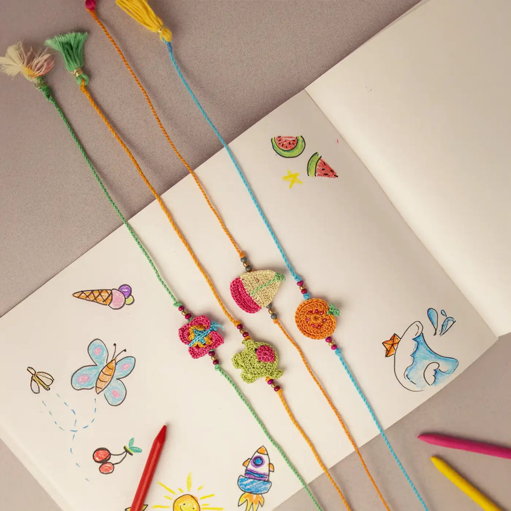 Handmade Crochet Funtime Rakhi With Roli Chawal Set Of 4 - Full view on sketchbook background