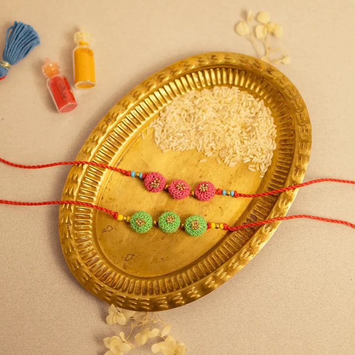Handmade Crochet Round Ananta Rakhi With Roli Chawal Set Of 2 - Two bracelets displayed flat